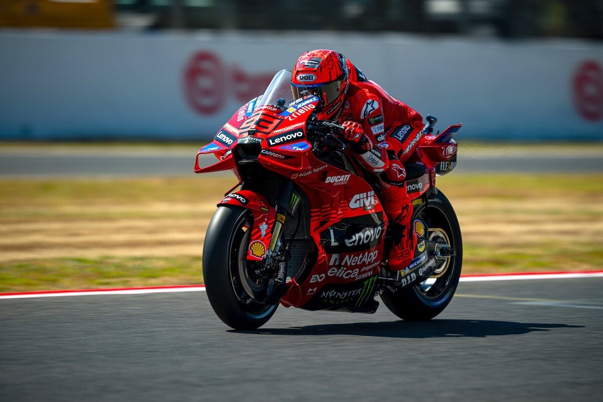 Moto GP pilota in azione su circuito, motociclista professionista su Ducati con sponsor Lenovo e Monster, competizione di alta velocità, sport motoristici, gare di motociclismo.