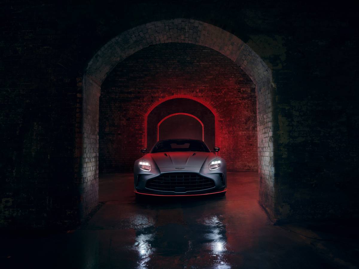 Frontale Aston Martin Vantage S illuminato di rosso sotto archi in mattoni