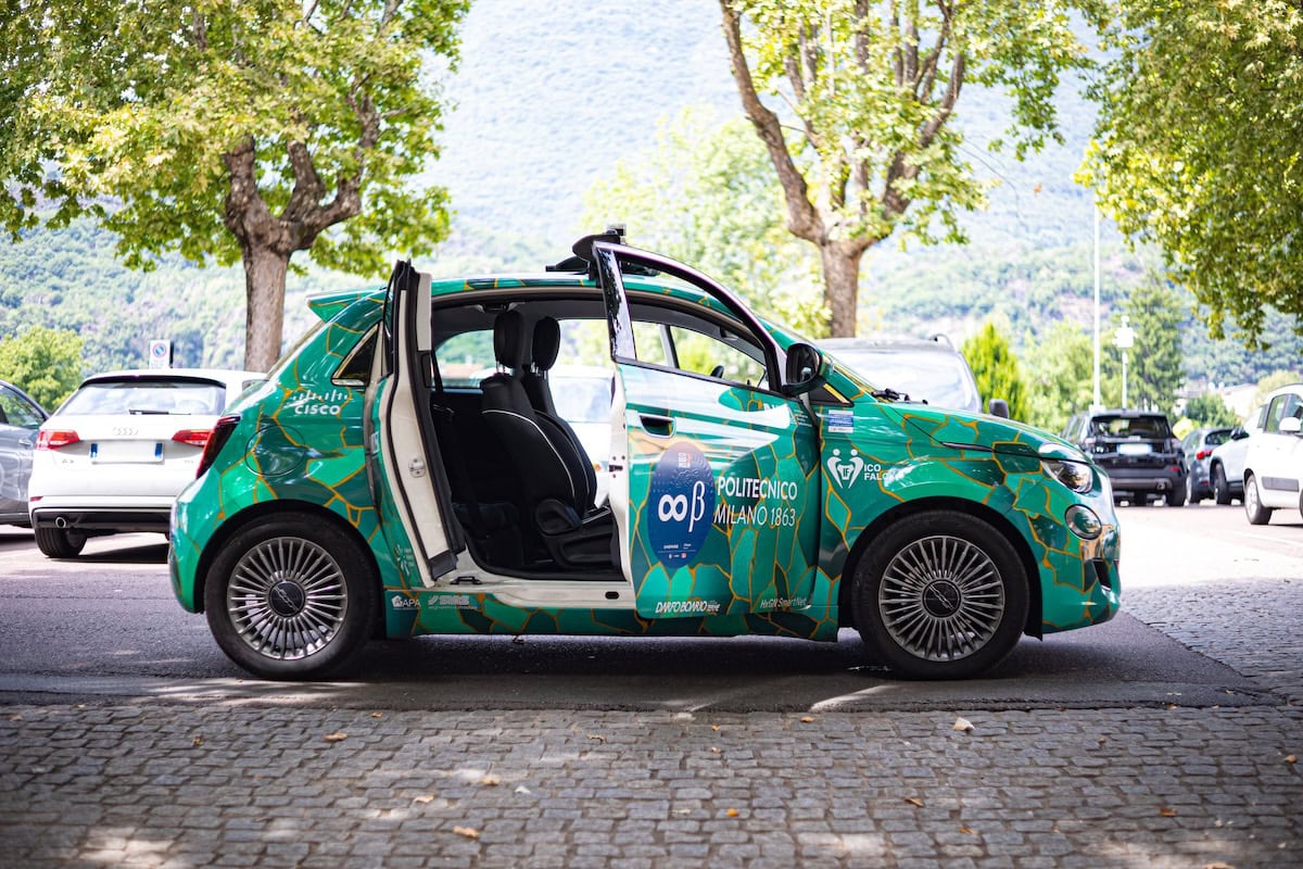 Fiat 500e del Politecnico di Milano parcheggiata con porte aperte e livrea verde decorata