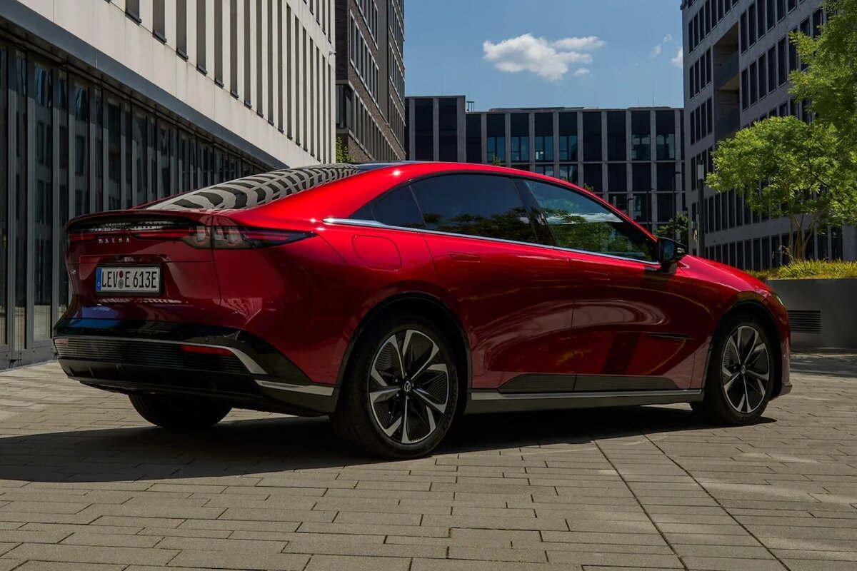 Mazda 6e 2025 EV rossa fotografata in contesto urbano sotto il sole.