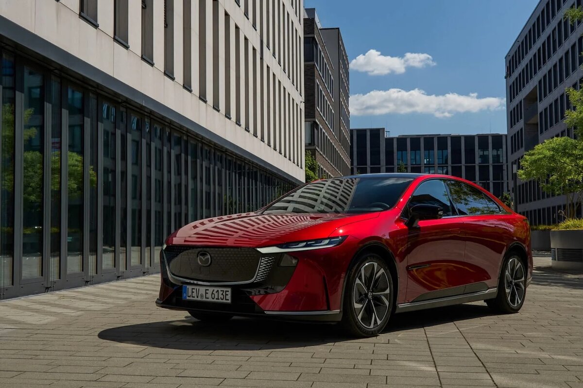 Mazda 6e 2025 parcheggiata in ambiente urbano moderno vista da tre quarti posteriore.