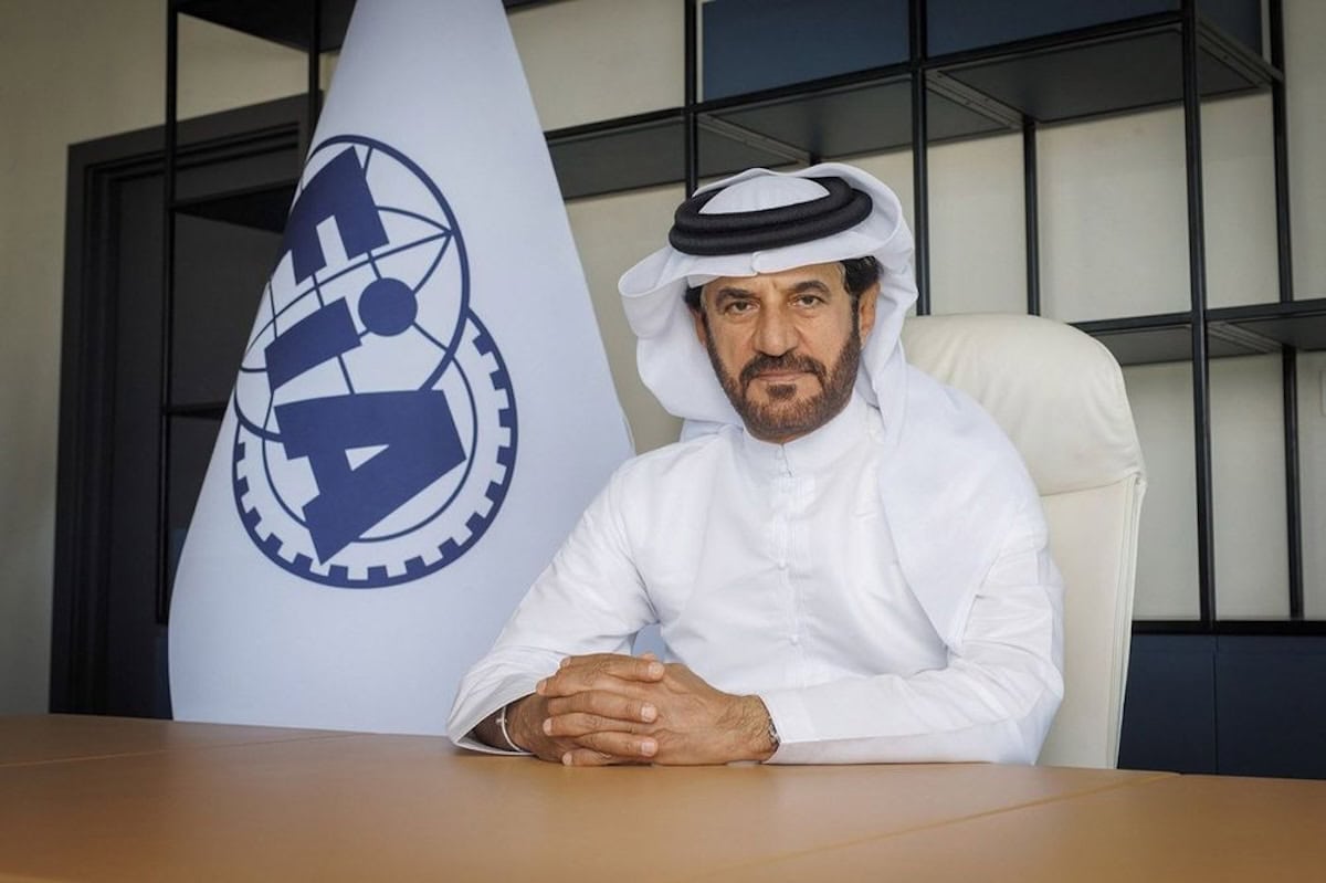 Ritratto ufficiale di Mohammed ben Sulayem presidente FIA in abito tradizionale accanto alla bandiera dell'organizzazione automobilistica