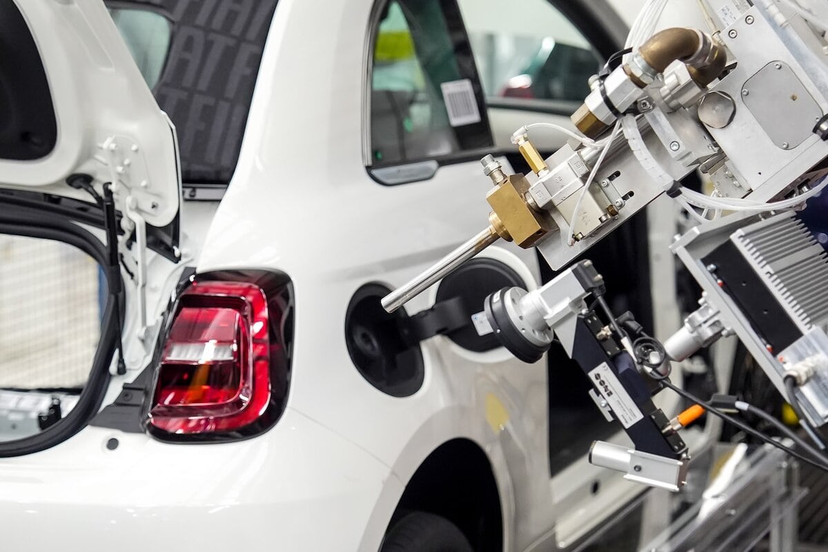 Braccio robotico effettua test su Fiat 500 ibrida bianca durante la fase di produzione in linea di assemblaggio nello stabilimento Mirafiori Torino