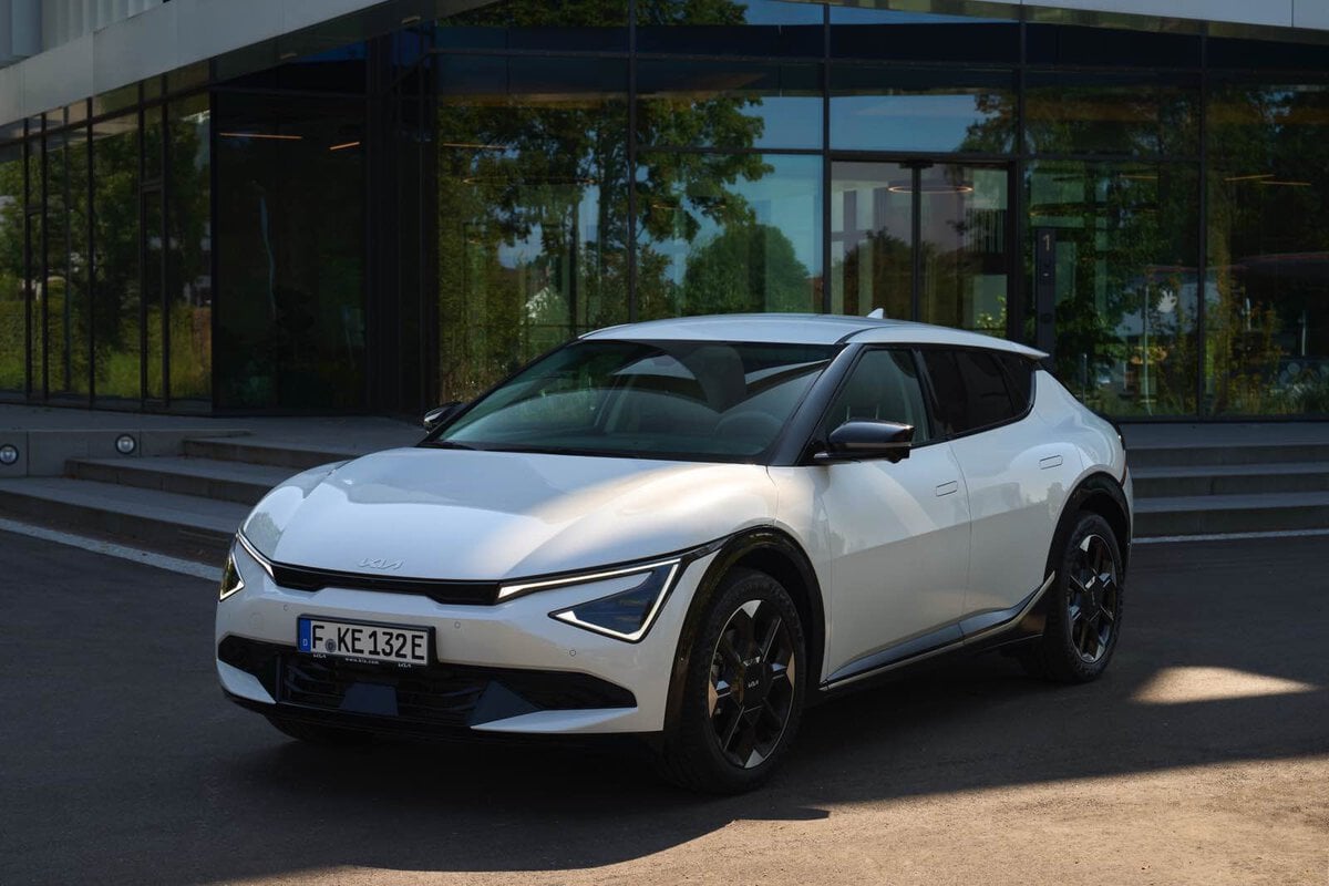 Nuova Kia EV6 2025 bianca parcheggiata davanti a un edificio con vetrate e design contemporaneo.