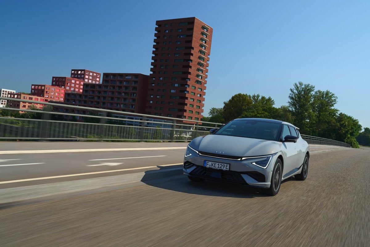  Kia EV6 grigia in marcia su ponte cittadino con edifici residenziali moderni sullo sfondo.