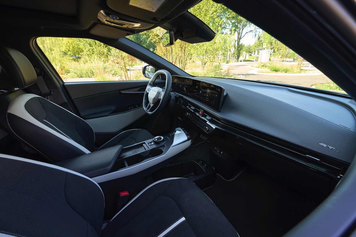 Vista lato guida della Kia EV6 con sedili sportivi, display widescreen e finiture moderne in nero e grigio.