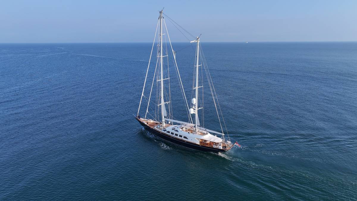 Superyacht a vela Perini refittato naviga in mare aperto, scafo scuro, ponte in teak, doppio albero maestoso.