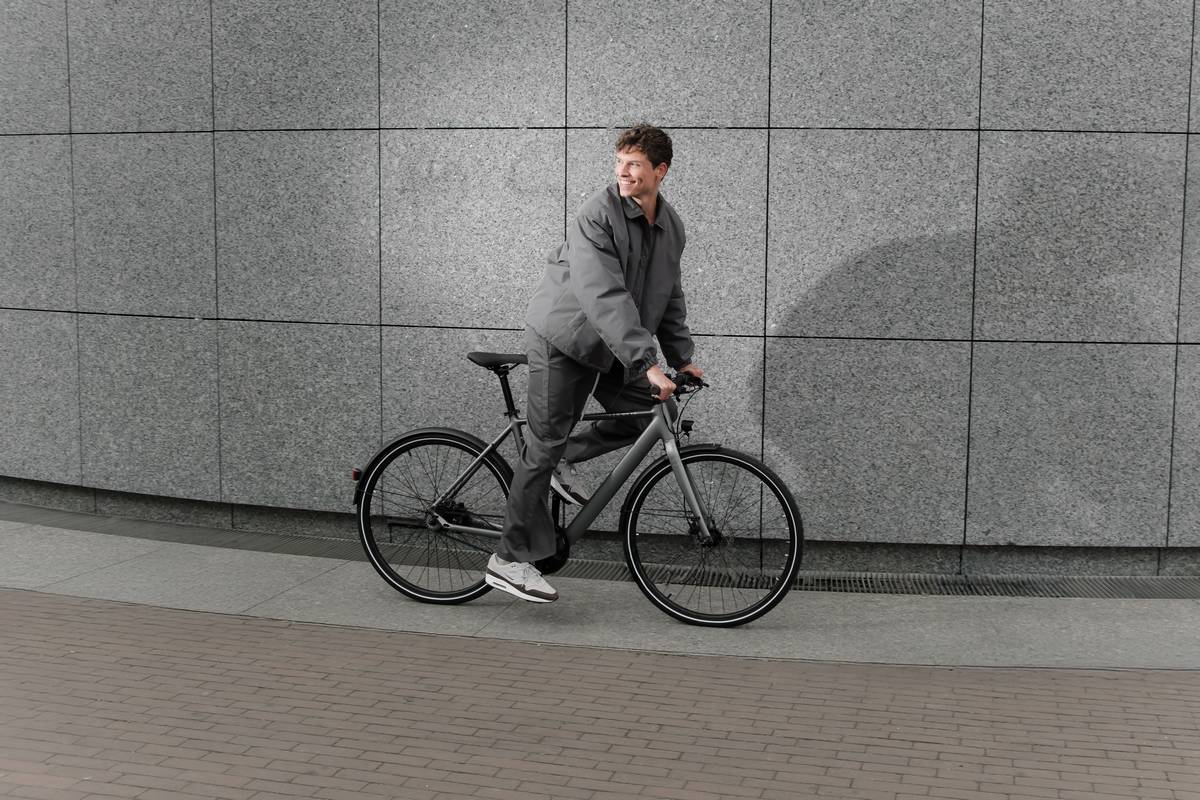 Bicicletta elettrica Tenways CGO600 grigia, uomo che pedala in città, stile minimal, uso quotidiano urbano.