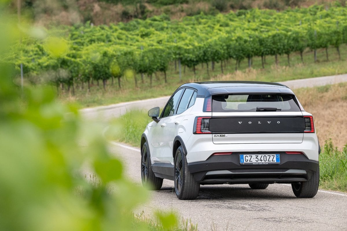 Vista posteriore della Volvo EX30 Cross Country MY26 su strada di campagna con vigneti sullo sfondo.
