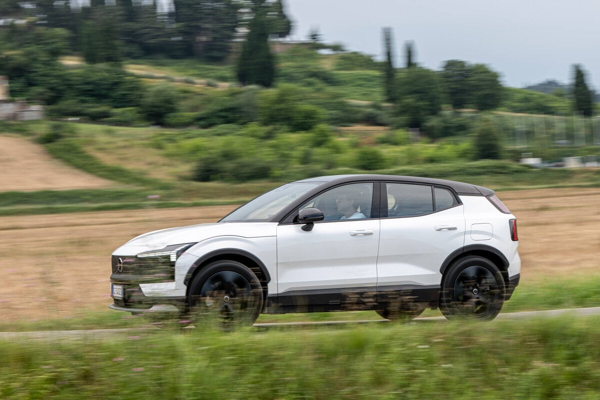 Volvo EX30 Cross Country MY26 in corsa laterale su una strada di campagna verdeggiante.