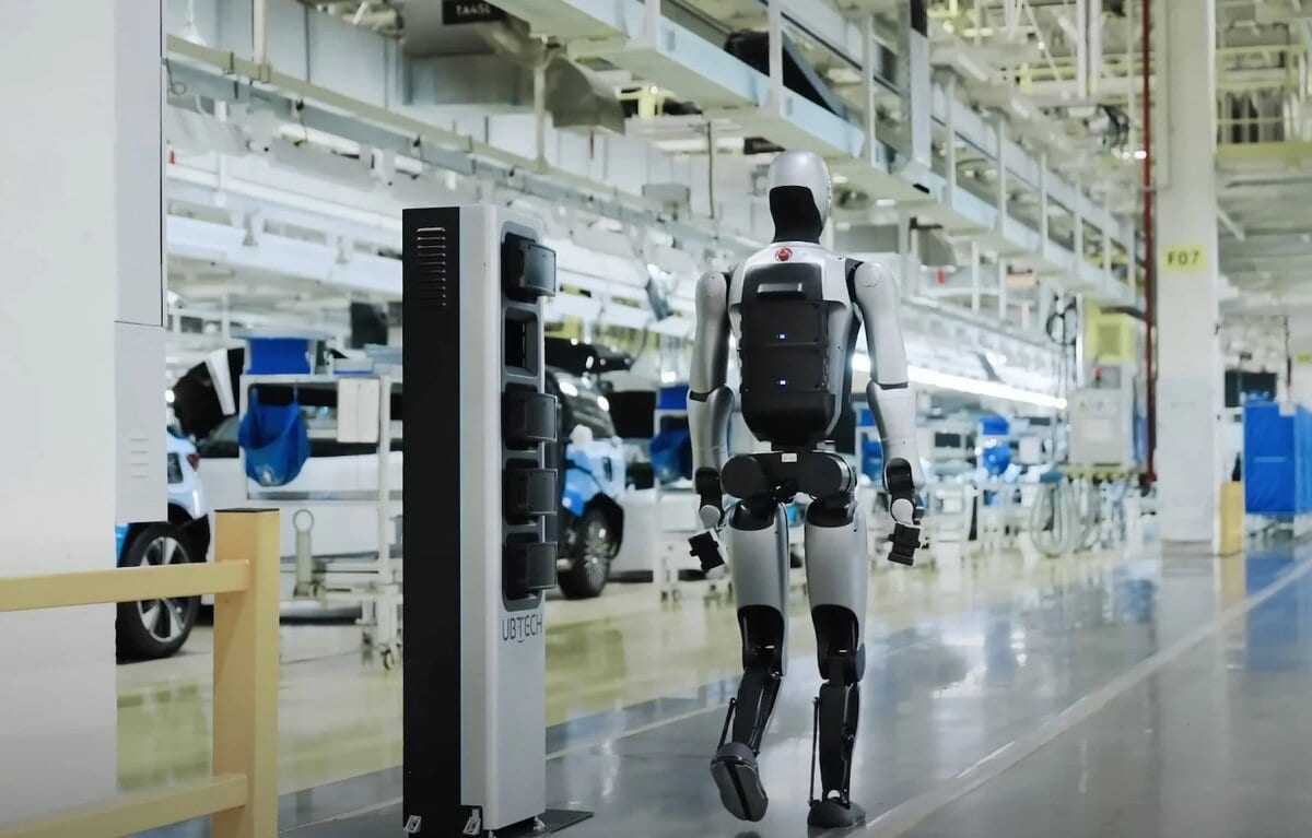 Il robot umanoide Walker S2 cammina in una fabbrica automobilistica tra veicoli in produzione.