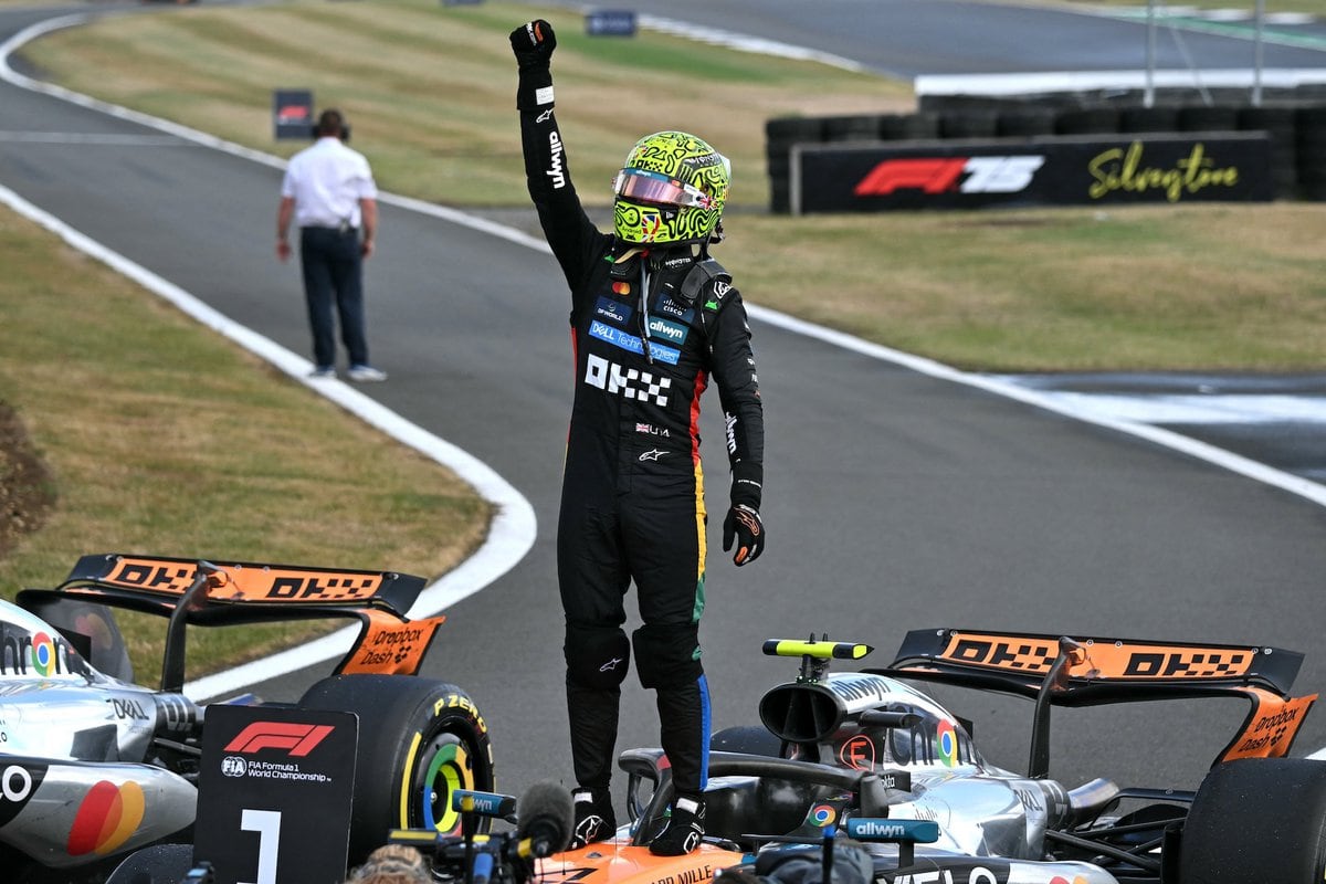 Lando Norris esulta in tuta McLaren accanto alla sua monoposto numero 4, dopo la vittoria nel GP di Formula 1.