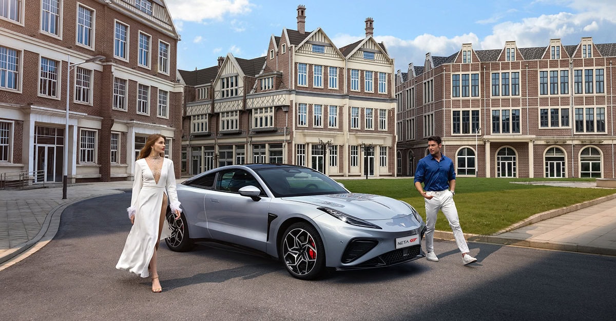 Neta GT parcheggiata con due modelli accanto davanti a edifici in stile europeo