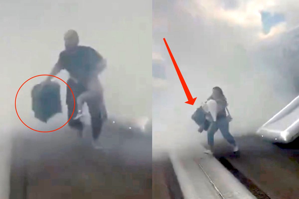 Due passeggeri scendono da un aereo in fumo usando lo scivolo di emergenza, entrambi portano con sé bagagli a mano nonostante l'evacuazione.