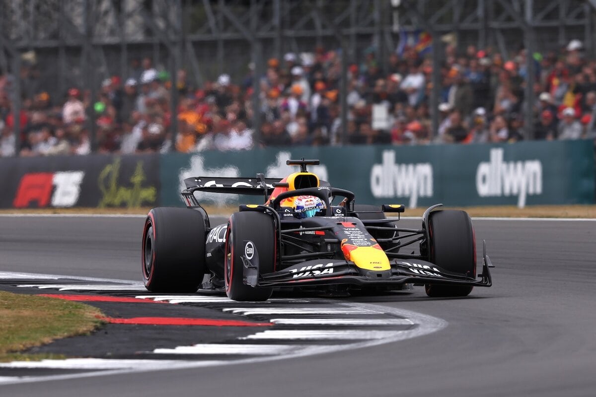 Red Bull RB20 nera e rossa numero 1 di Max Verstappen affronta una curva a Silverstone, inquadrata frontalmente con il pubblico sullo sfondo.