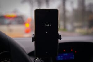 Smartphone su supporto da cruscotto con schermo acceso in un’auto ferma nel traffico, visibile sfondo sfocato con luci freno