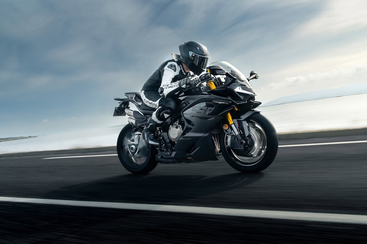 Pilota in piega su CFMoto 750SR-S nera lungo strada panoramica sul mare.