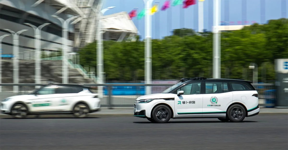 Due robotaxi autonomi Apollo GO della flotta Pony.ai in movimento su strada cittadina, con sensori visibili sul tetto e scritte in cinese sulle fiancate.