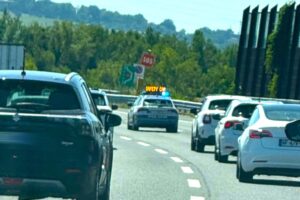 Auto della polizia con scritta Safety Car guida il traffico in autostrada tra altre vetture.