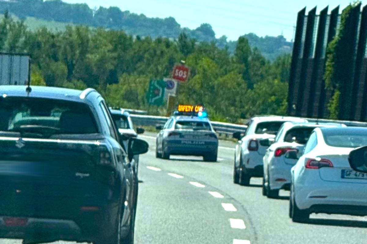 Auto della polizia con scritta Safety Car guida il traffico in autostrada tra altre vetture.