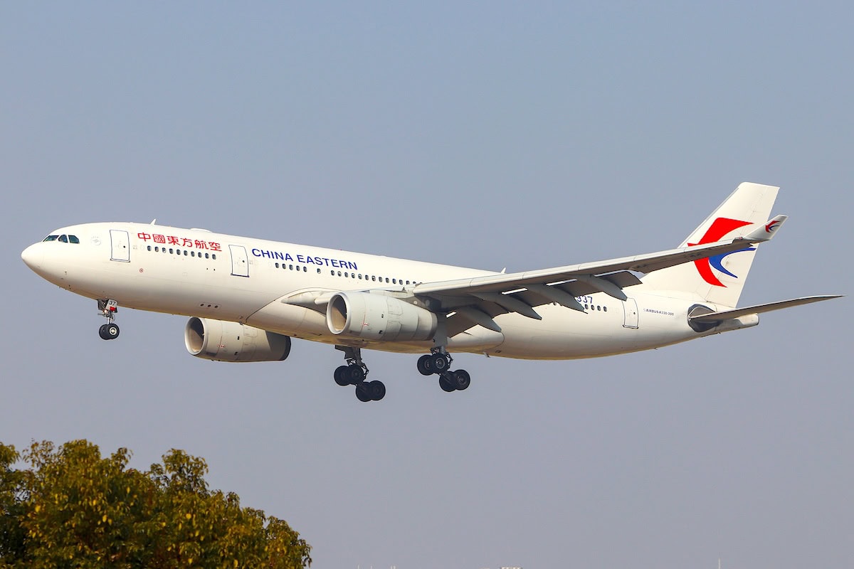 Aereo Airbus A330-243 della compagnia China Eastern Airlines in fase di atterraggio con carrello estratto, cielo sereno sullo sfondo.