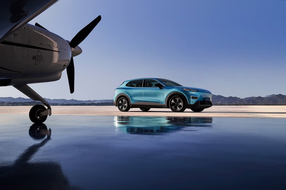 Deepal S05 parcheggiato accanto a un aereo privato in un hangar moderno, con sfondo montuoso.