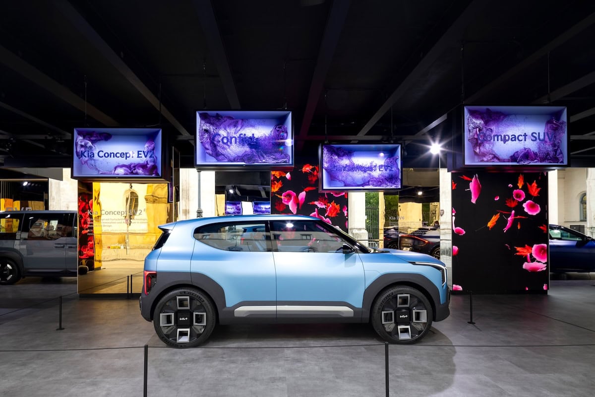 Il SUV compatto Kia Concept EV2 in mostra nello stand Kia allo IAA Mobility 2025, con pannelli LED e schermi digitali sopra l’auto.