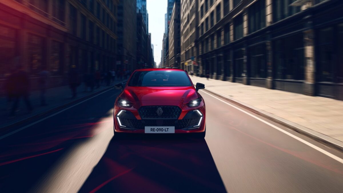 Nuova Renault Clio E-Tech rossa in movimento su una strada cittadina, con effetto dinamico e giochi di luce sulle superfici del cofano.