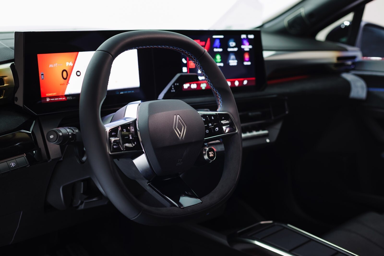 Cruscotto digitale della Renault Clio E-Tech con doppio schermo, volante multifunzione e cuciture blu a contrasto, in un interno high-tech.