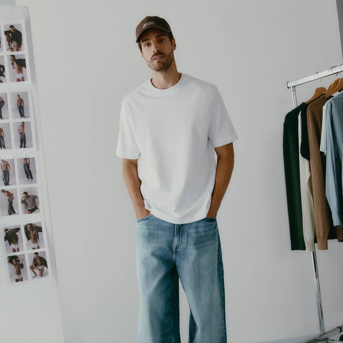 Casco maschio in bianco casual con jeans larghi e cappello in look street style.