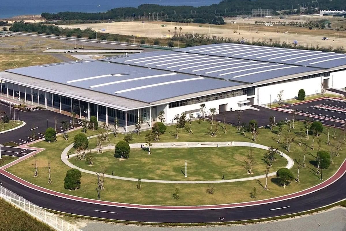 ista aerea della centrale ad osmosi inversa di Fukuoka in Giappone, con tetto coperto da pannelli solari, ampi parcheggi e aree verdi ben curate nelle vicinanze.