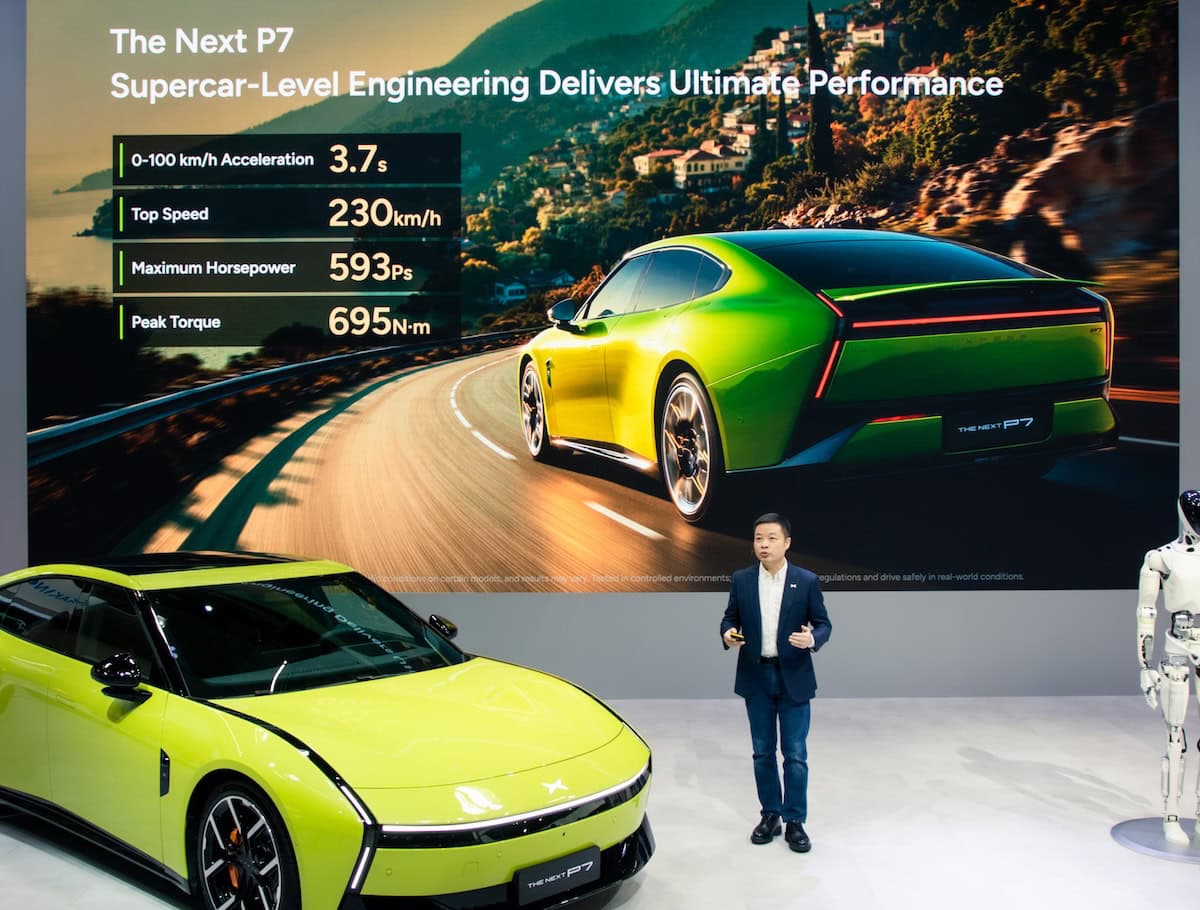 Il nuovo XPeng P7 in versione sportiva lime durante la presentazione ufficiale, con specifiche tecniche evidenziate su maxi schermo e un robot in esposizione.