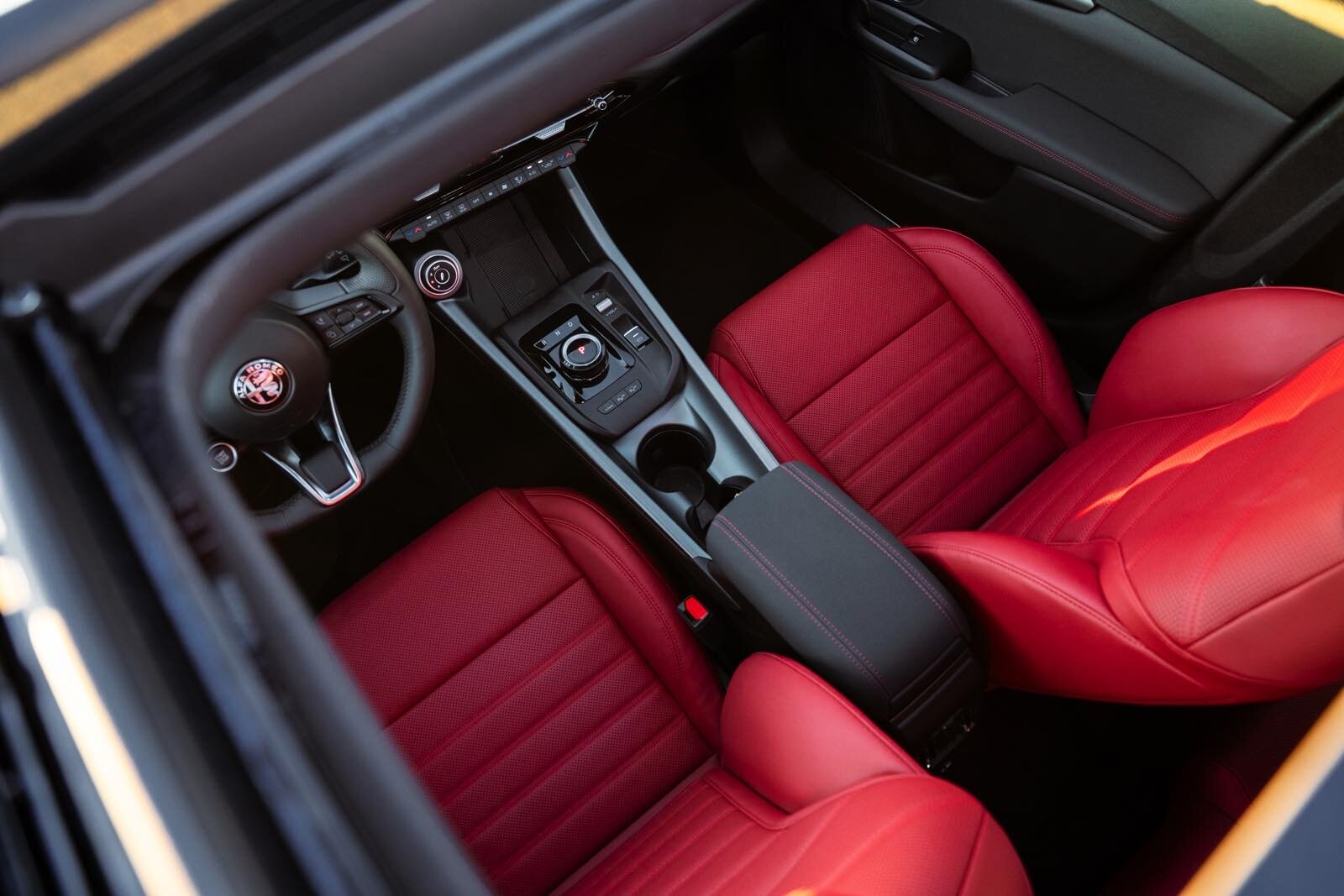 Sedili sportivi in pelle rossa e volante sportivo all’interno di un’auto di lusso Alfa Romeo Tonale MY 2026.