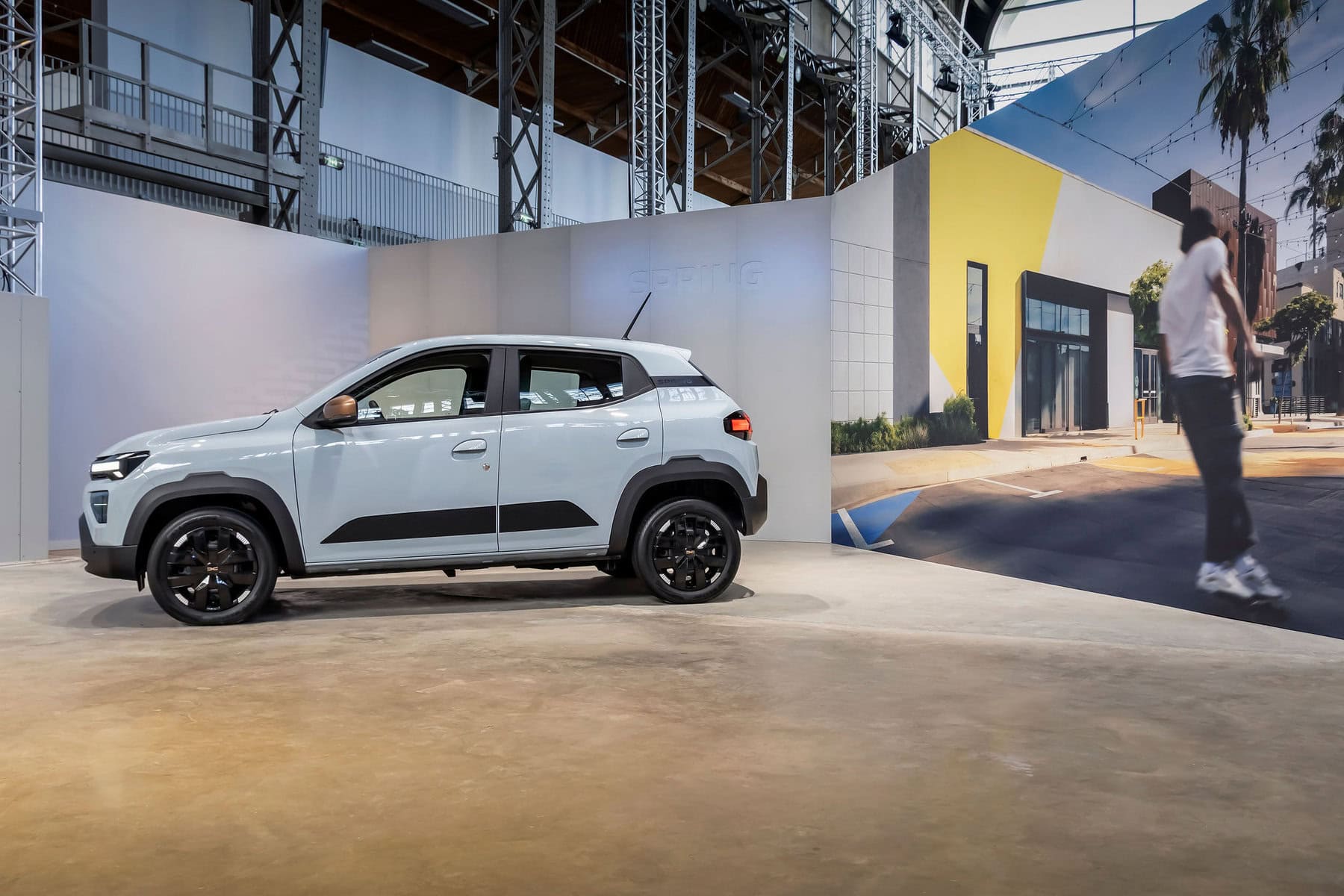 Auto elettrica compatta Dacia Spring 2026 presso uno stand di esposizione in un centro fieristico.