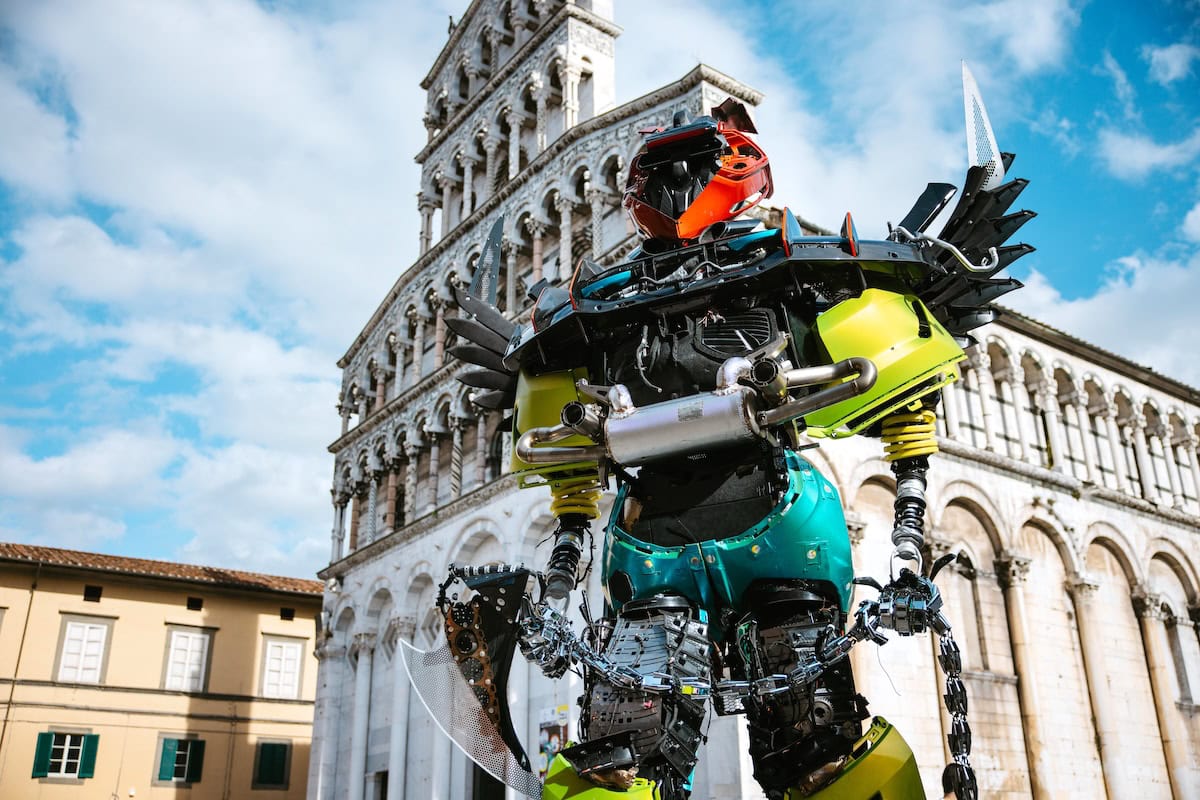 Motore robotico in stile fantascienza davanti al duomo di pisa, scultura tecnologica futuristica, installazione artistica innovativa, rappresentazione di intelligenza artificiale e robotica, scultura moderna e avveniristica.