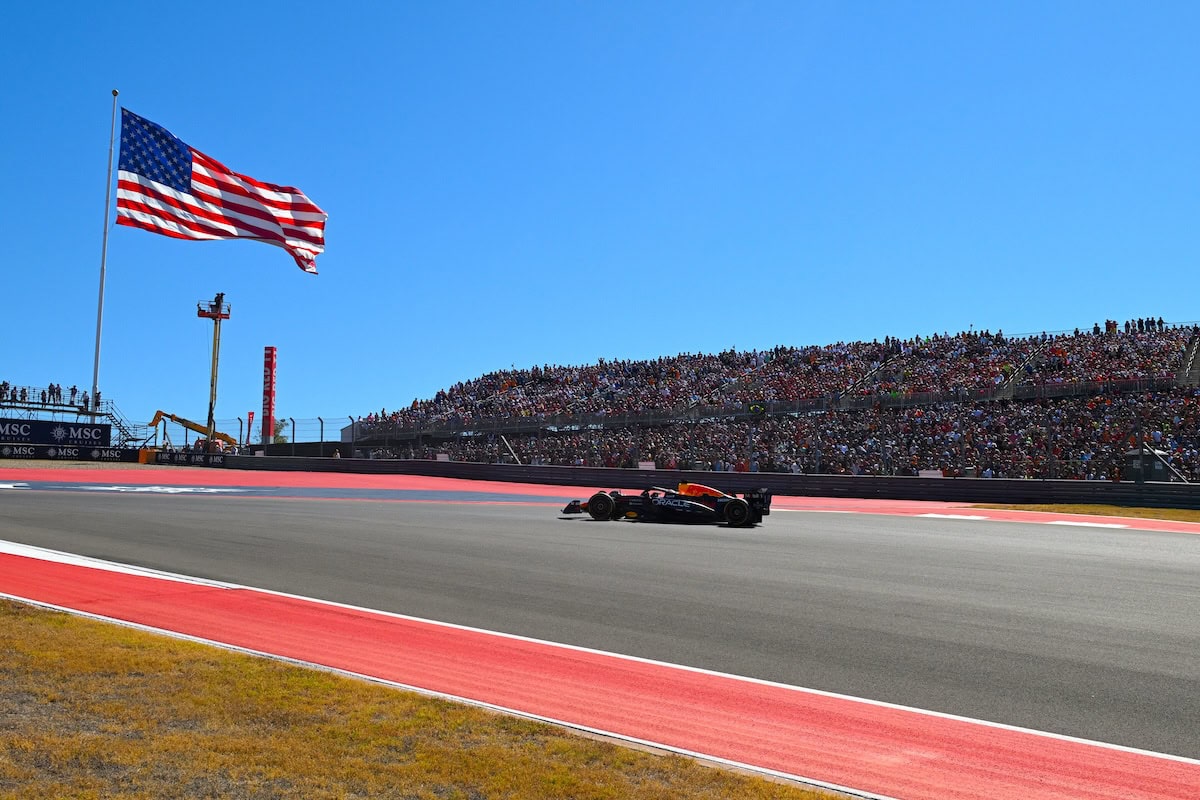 Auto da corsa Red Bull F1 sul circuito di Austin con pubblico in tribuna e bandiera americana al vento, alta velocità e passione per la Formula 1.