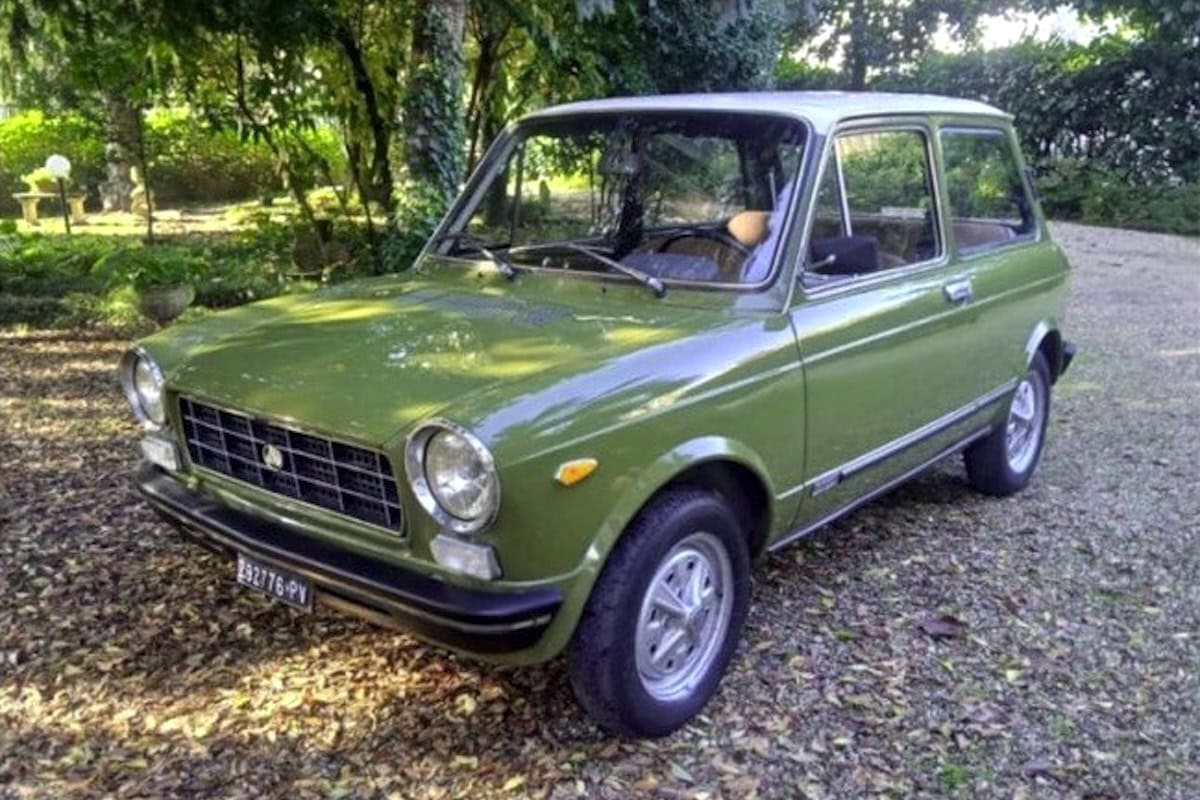 Auto d'epoca Fiat 128 in verde in un giardino alberato, modello vintage, perfetta per collezionisti.