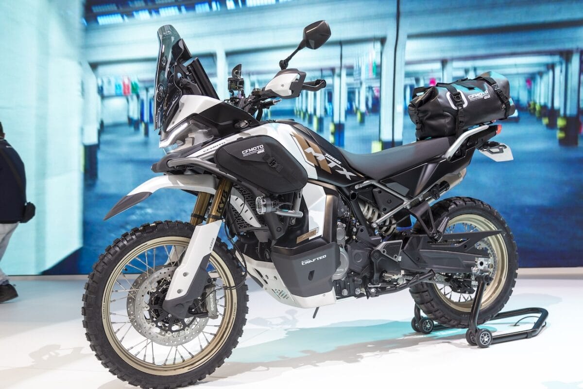 Moto adventure elettrica CFMOTO 1000MT-X con pneumatici tassellati e borse laterali, design robusto e tecnologia avanzata per viaggi off-road.