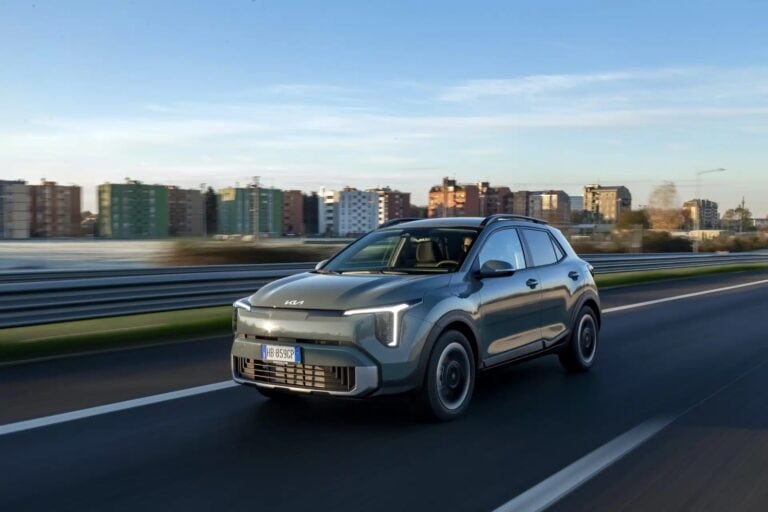 Auto Kia Stonic 2026 in corsa su strada urbana con skyline in background.