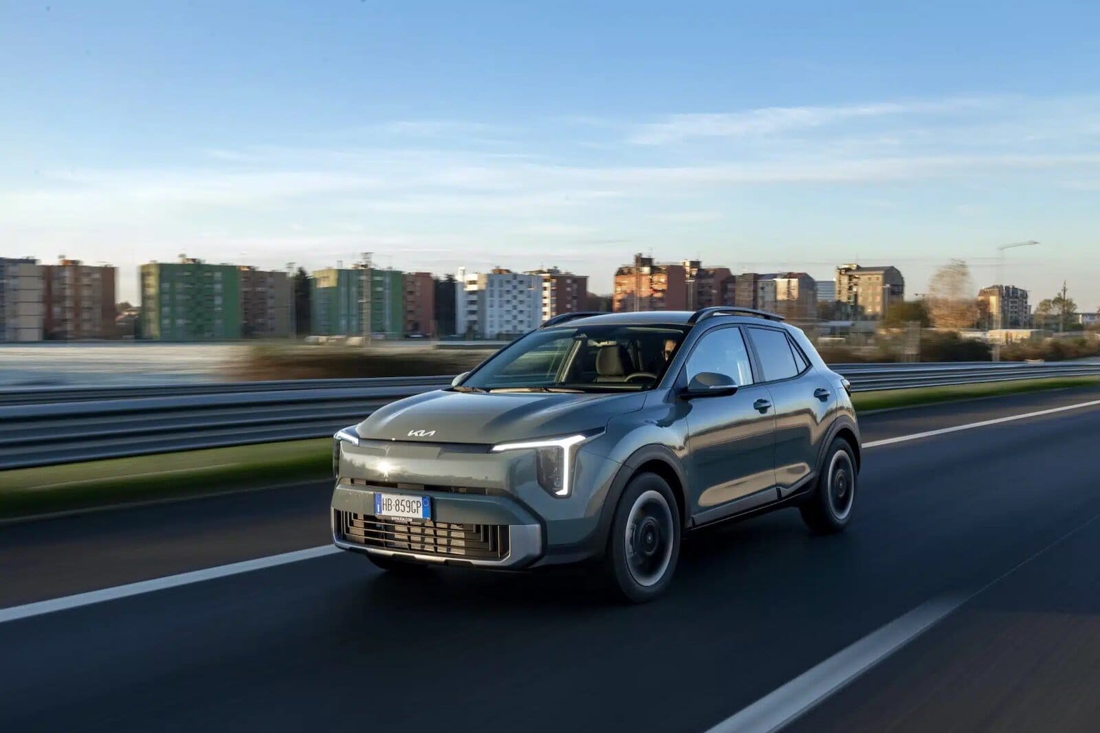 Auto Kia Stonic 2026 in corsa su strada urbana con skyline in background.