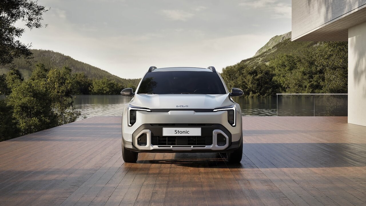 Auto KIA Stonic vista frontale su un lungolago naturale con montagne sullo sfondo, design moderno e sostenibile.