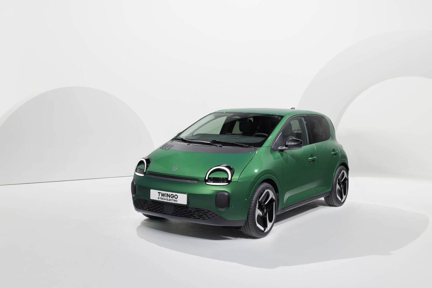 Piccolo veicolo elettrico Renault Twingo E-Tech Electric di colore verde su sfondo bianco; auto compatta, zero emissioni, city car, design moderno, eco-friendly, auto elettrica per città.
