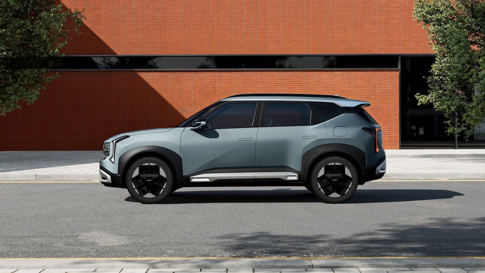 Auto SUV Kia Seltos 2026 dal design innovativo, su strada asfaltata con edificio in mattoni sullo sfondo.