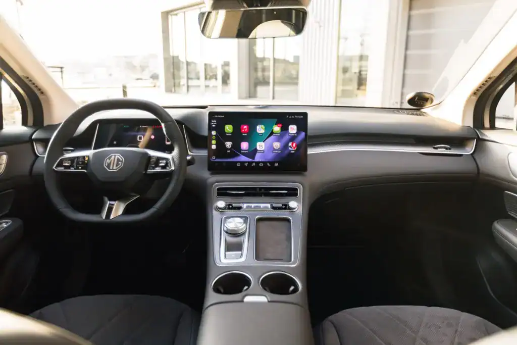 Interni moderni di un'auto MG con touchscreen e tecnologia all'avanguardia, doppi portabicchieri e navigazione integrata.