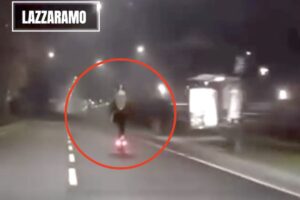 Immagine di uno scooter che sfreccia di notte su strada asfaltata con illuminazione pubblica, evidenziato da un cerchio rosso, in contesto urbano o periferico.