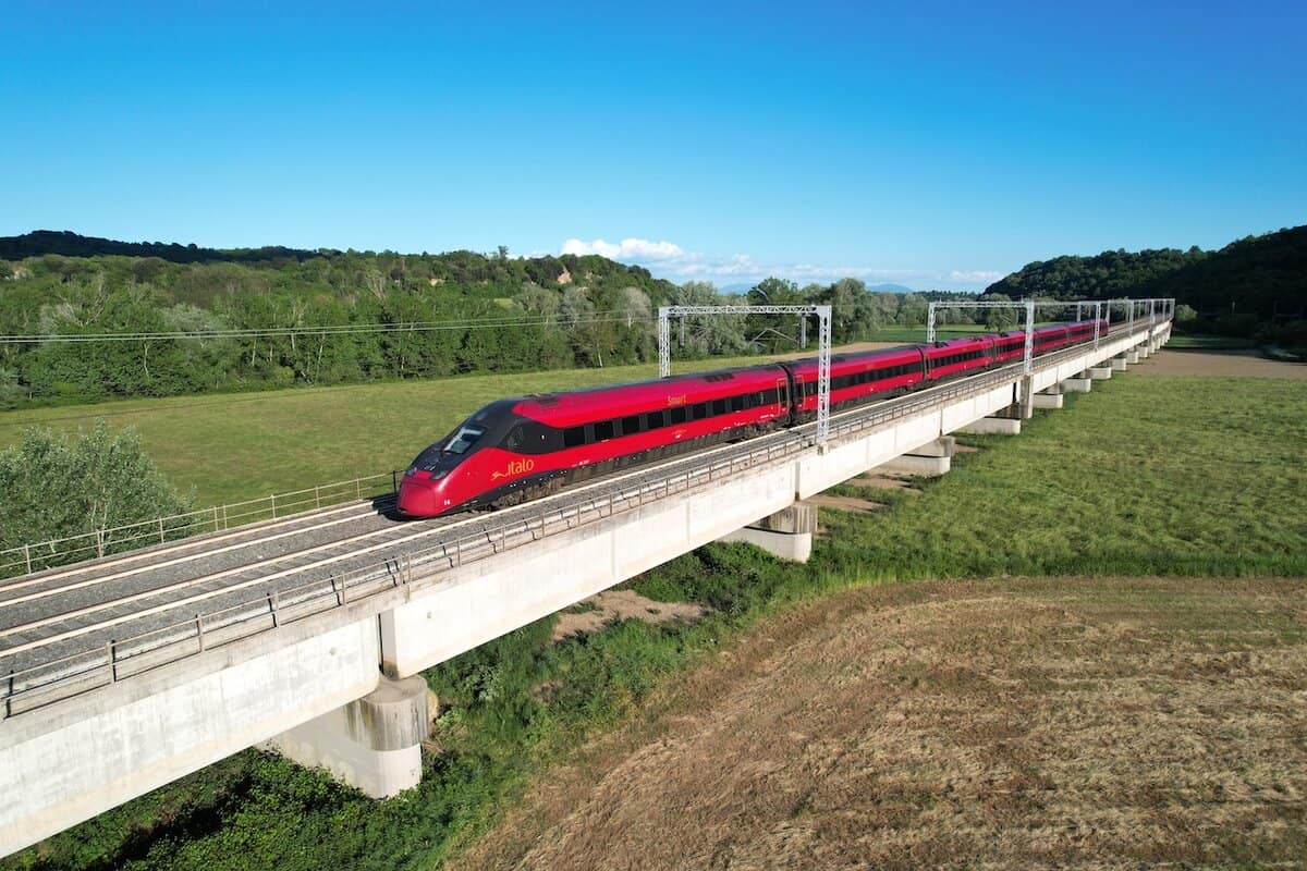 Treno Italo rosso ETR 675 EVO su viadotto in campagna, ripreso dall'alto mentre attraversa un paesaggio verde.