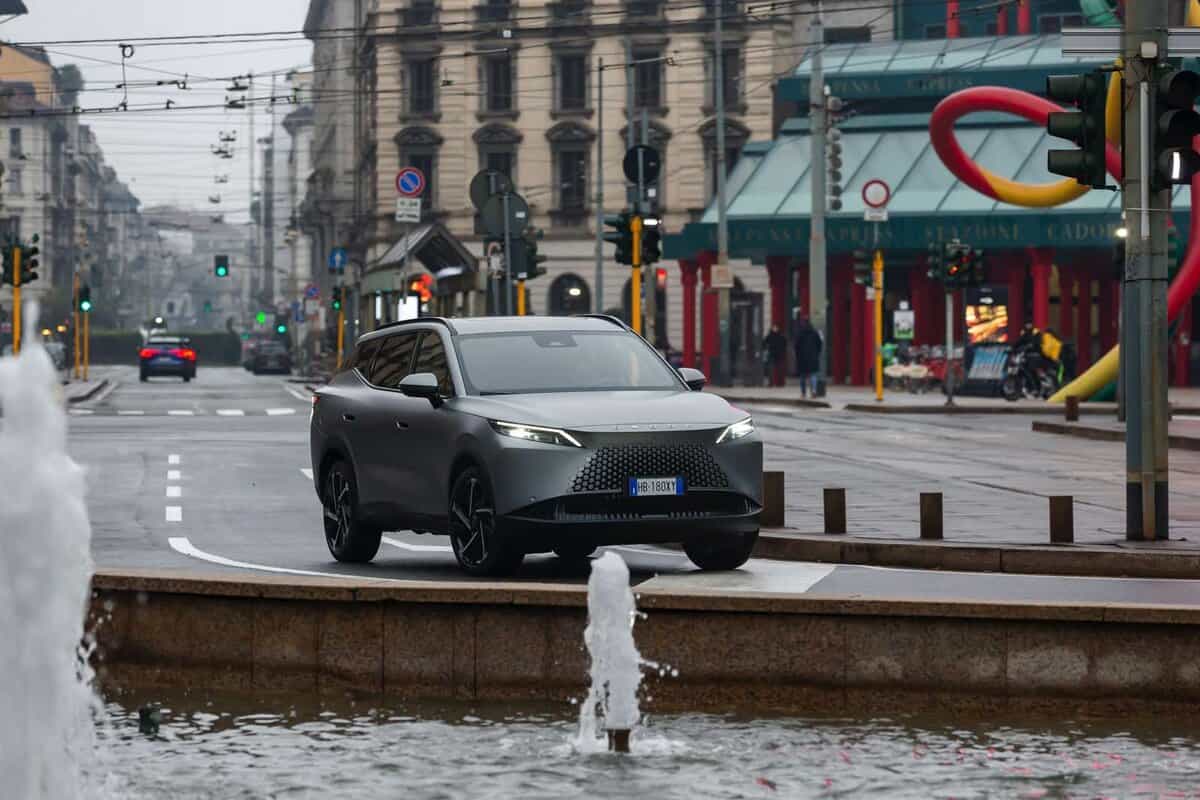 Omoda 7 SHS-P a Milano; design elegante; strada trafficata, edifici storici.