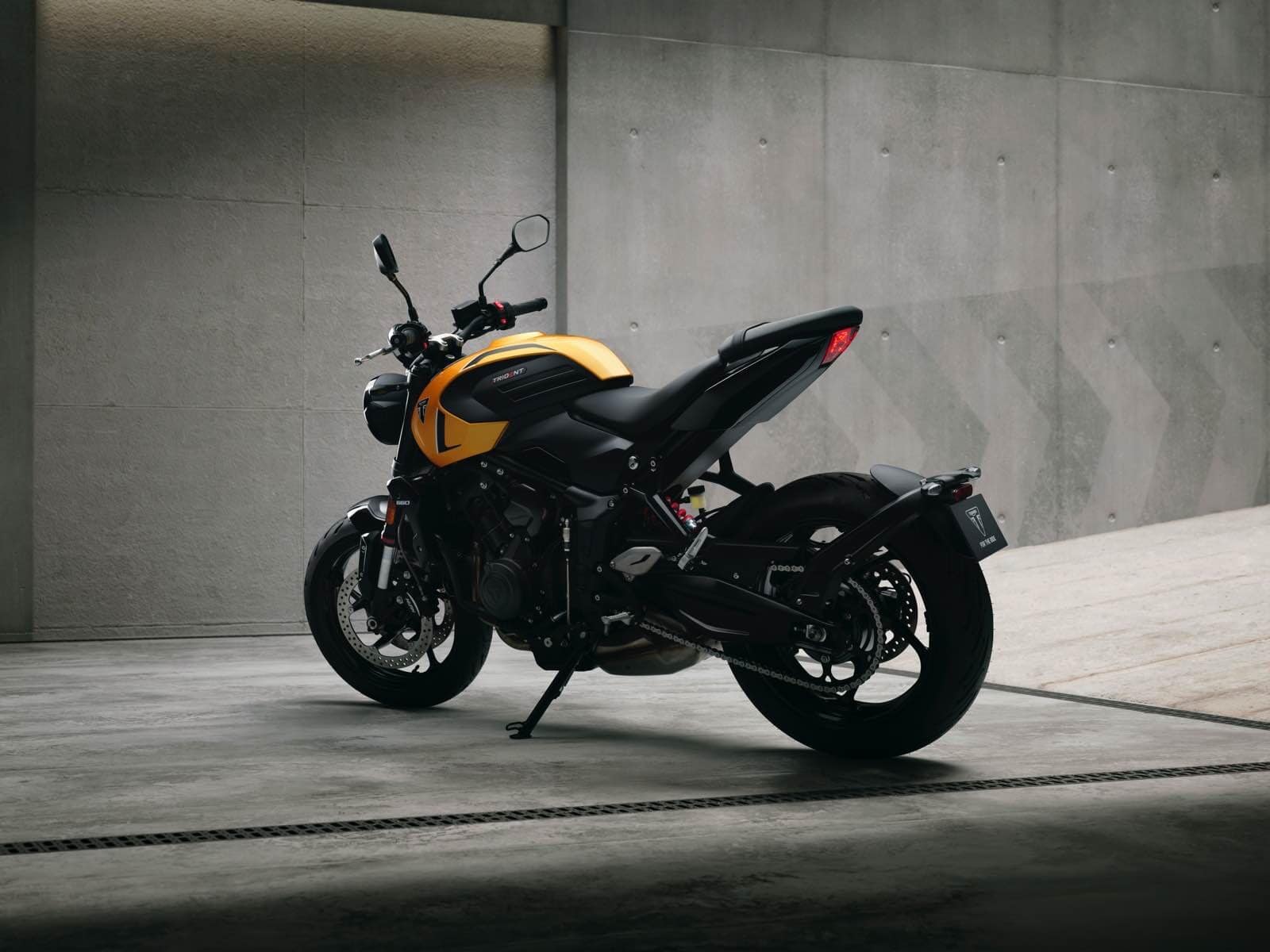 Triumph Trident 660 nera e gialla in un ambiente moderno e minimalista con pareti in cemento.