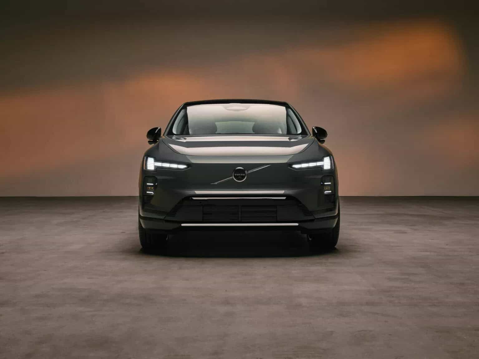 Volvo EX60 elettrica nera vista frontale, in studio con illuminazione calda. Design elegante e moderno.