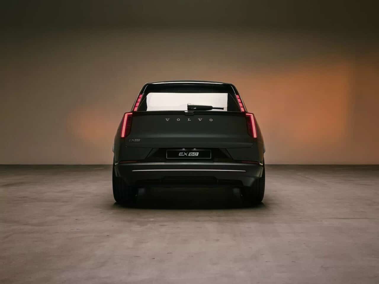 Volvo EX60 nera vista posteriore in studio con luce calda, auto elettrica compatta.
